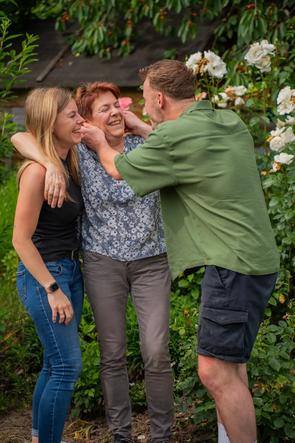 Familie umarmt sich im Garten, alle lächeln und haben Spaß.
