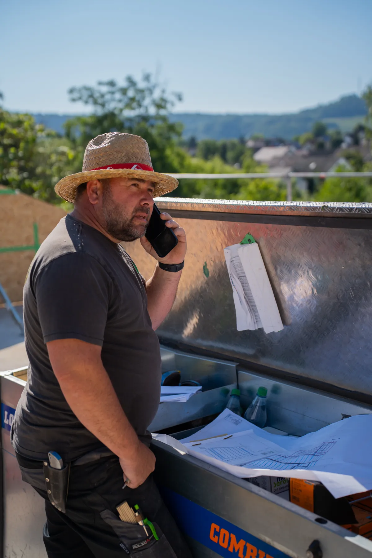 Bauleiter telefoniert vor Bauplänen auf der Baustelle.