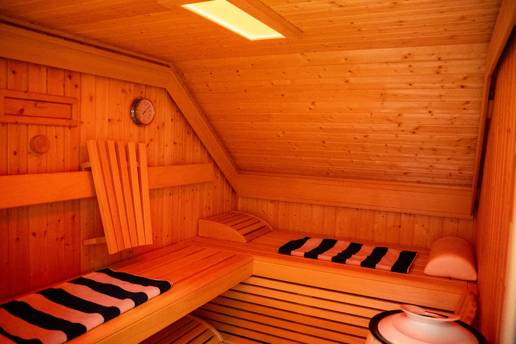 Holzsauna mit zwei Liegeflächen und hellem Innenlicht.