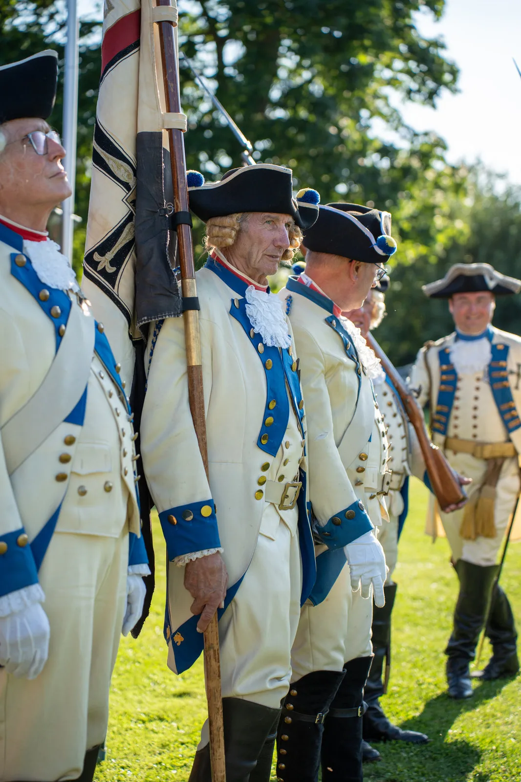 Ein Fahnenträger der historischen Garde steht mit der Standarte in der Reihe der Gardisten.