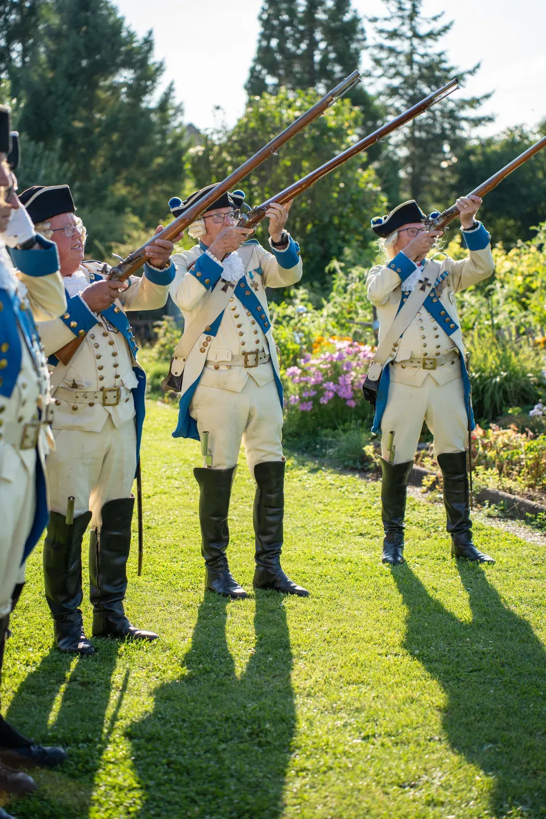 Salutschüsse beim Gartenfest: Die Gardisten feuern ihre Musketen ab, Rauch steigt auf.