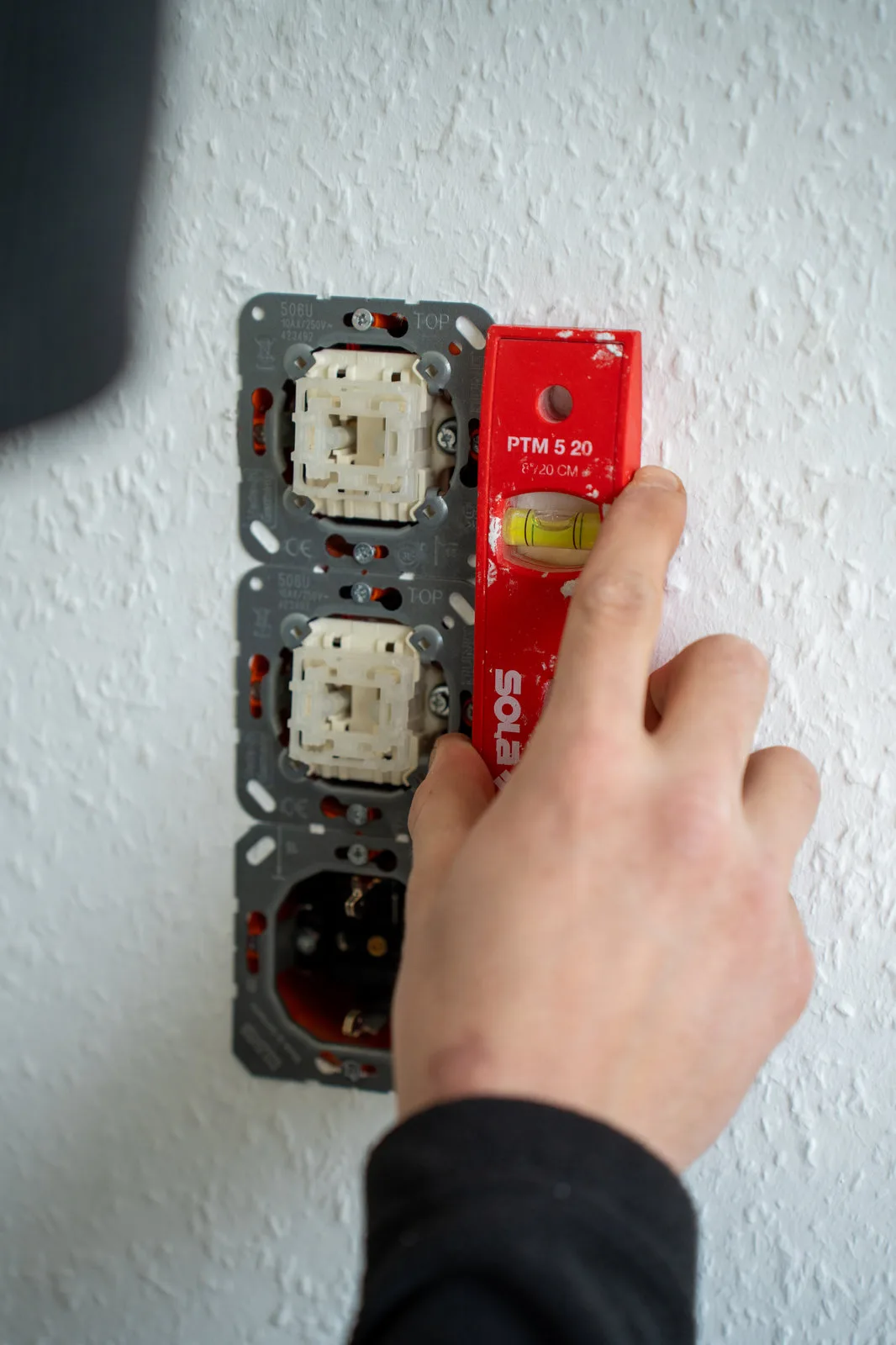Ein Elektriker richtet Unterputz-Schalterdosen mit einer kleinen Wasserwaage aus.
