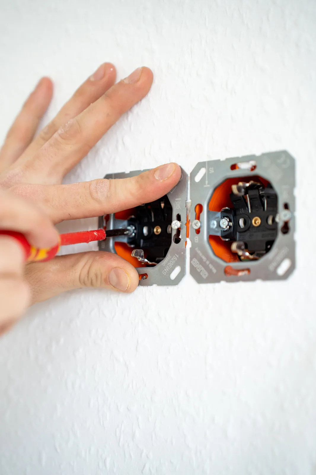 Feinarbeit an der Steckdose: Ein Elektriker justiert zwei Einsätze mit dem Schraubendreher.