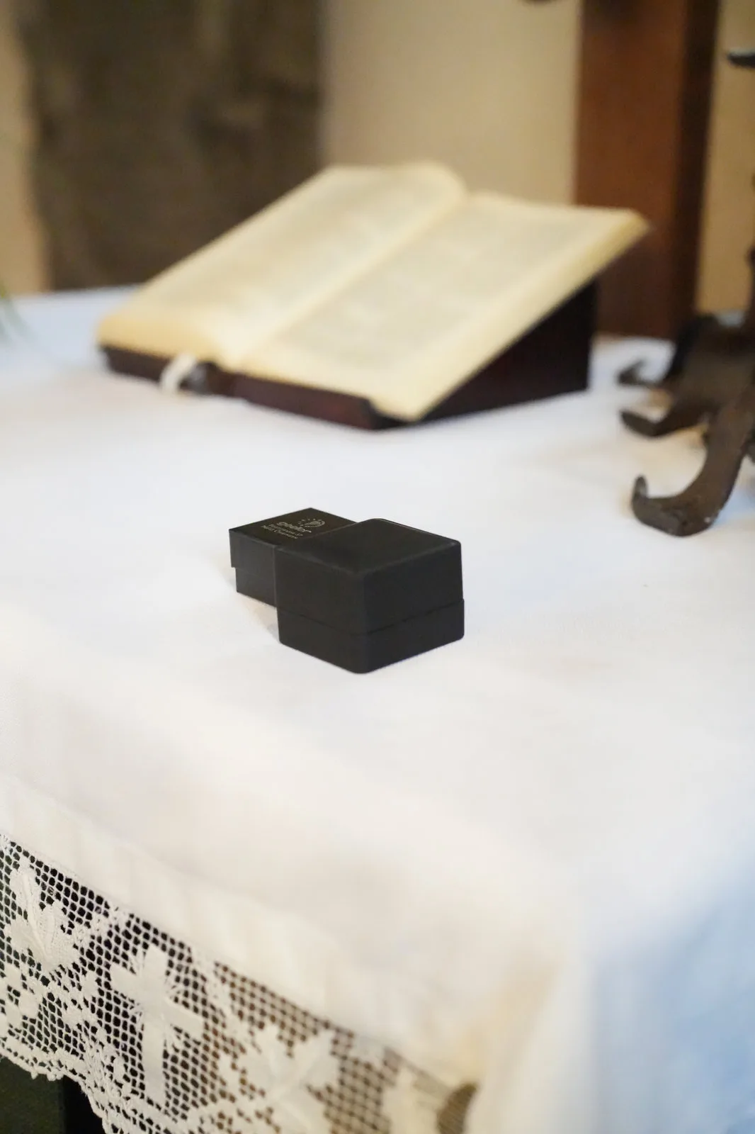 Schwarze Ringschatulle auf dem Altartuch, im Hintergrund eine aufgeschlagene Bibel.
