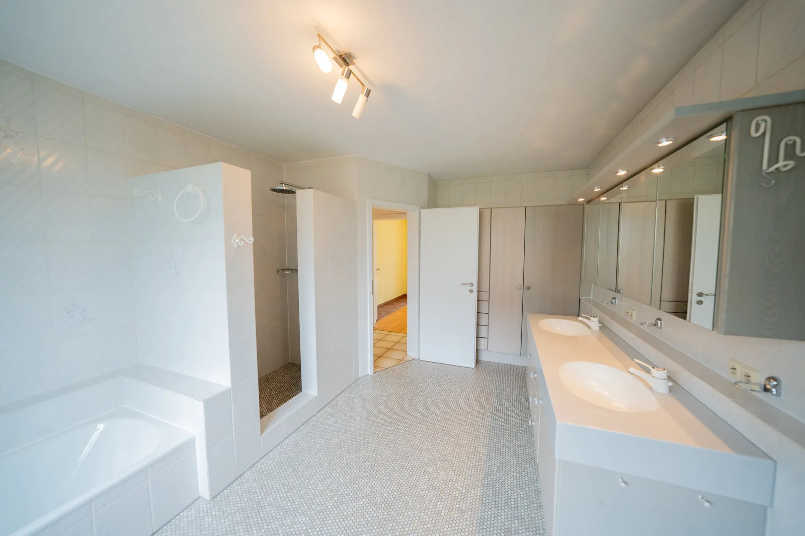 Geräumiges Badezimmer mit Eckwanne, offener Dusche und Doppelwaschtisch.