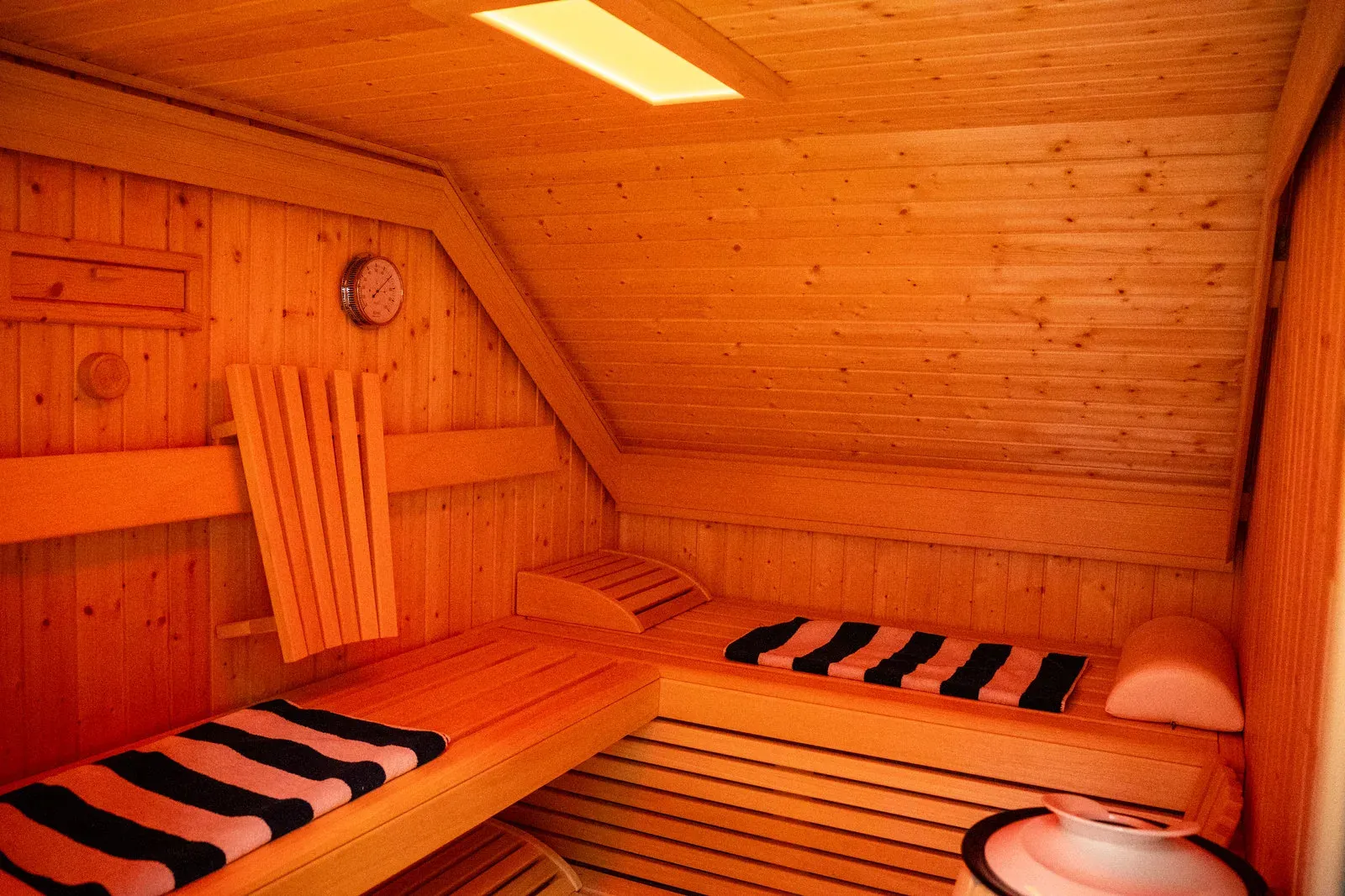 Blick in die holzvertäfelte Sauna mit gestreiften Handtüchern auf den Bänken.